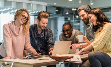 Group of young nonprofit employees collaborate around a laptop with free conferencing software