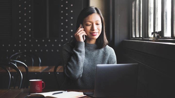 Femme au téléphone assise avec son ordinateur