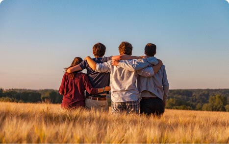 sich in einem Feld umarmende Gruppe